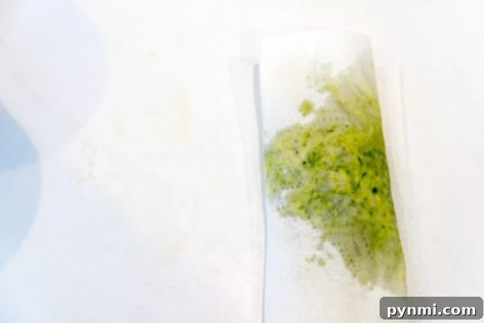 Wholesome Pumpkin Zucchini Muffins 3 Shredded zucchini being pressed between paper towels to remove excess moisture.