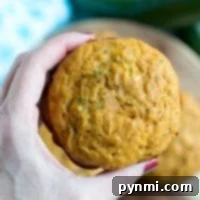 Wholesome Pumpkin Zucchini Muffins 7 Hand holding a freshly baked pumpkin zucchini muffin.