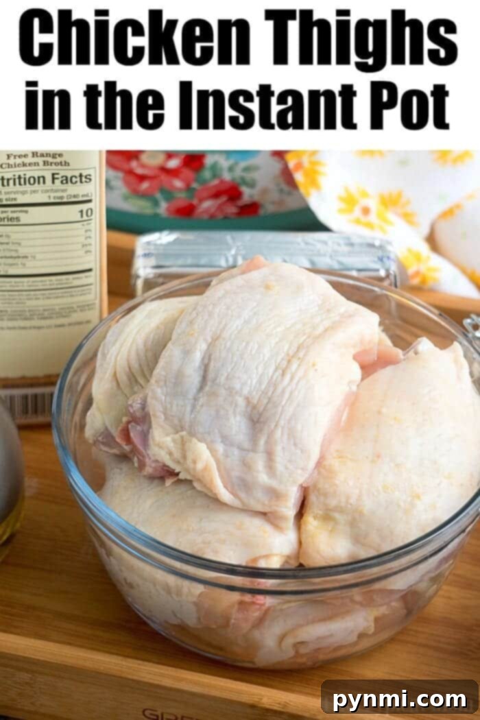 Raw bone-in chicken thighs in a glass bowl on a kitchen counter, next to chicken broth and an Instant Pot