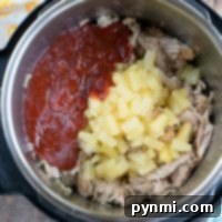 Instant Pot Hawaiian pulled pork with tender shredded pork, juicy pineapple chunks, and a rich red sauce on top.