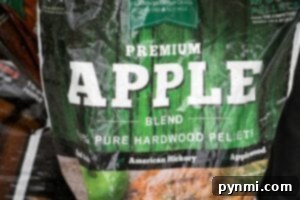 A bag labeled 'Premium Apple Blend' from Green Mountain Grills. The bag features a vibrant green woodgrain background with text highlighting the 100% pure hardwood pellets, ideal for infusing a rich applewood flavor into smoked dishes like beer can chicken.