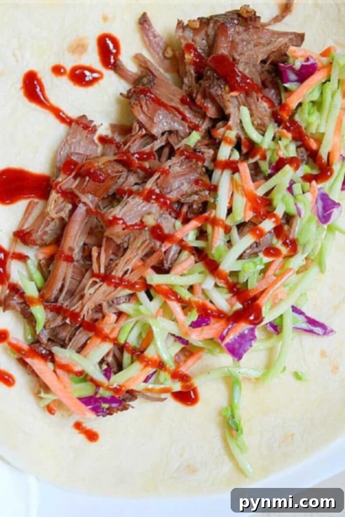Slow cooker Korean beef, slaw, and red sauce on a tortilla, ready to be wrapped.