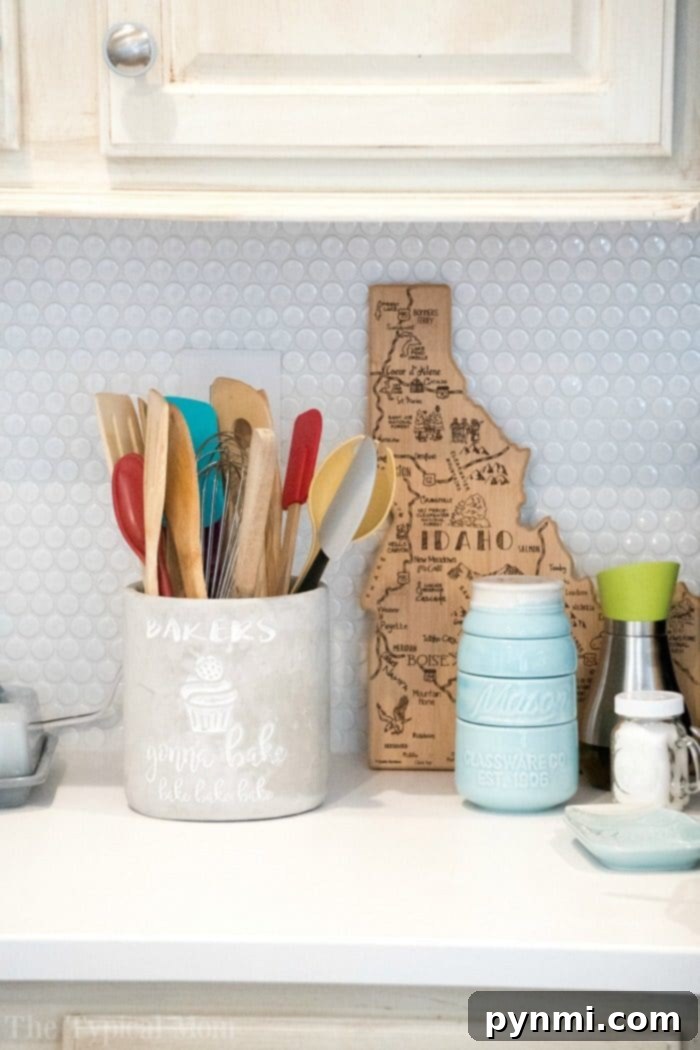 Our beautiful white penny tile backsplash perfectly complements our Farmhouse kitchen! Here's a peek at how we transformed our dark kitchen into a bright room with fun Farmhouse kitchen decor and a barn door pantry everyone loves! #farmhouse #decor #masonjar #barndoor #decorating #kitchen #table #lights #chairs White Penny Tile Backsplash Farmhouse Kitchen