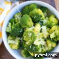 A bowl of perfectly steamed Instant Pot broccoli, garnished with fresh herbs and a sprinkle of cheese.