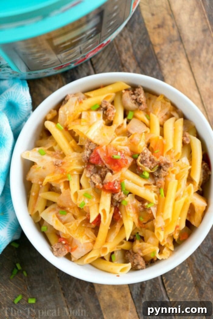 A beautifully presented bowl of pressure cooker penne pasta with ground sausage, diced tomatoes, and tender cabbage, garnished with fresh green onions. A side of crisp raw cabbage adds a textural contrast, all resting on a rustic wooden table.
