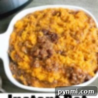 Instant Pot sweet potato casserole in a white dish beside an Instant Pot on a wooden table.