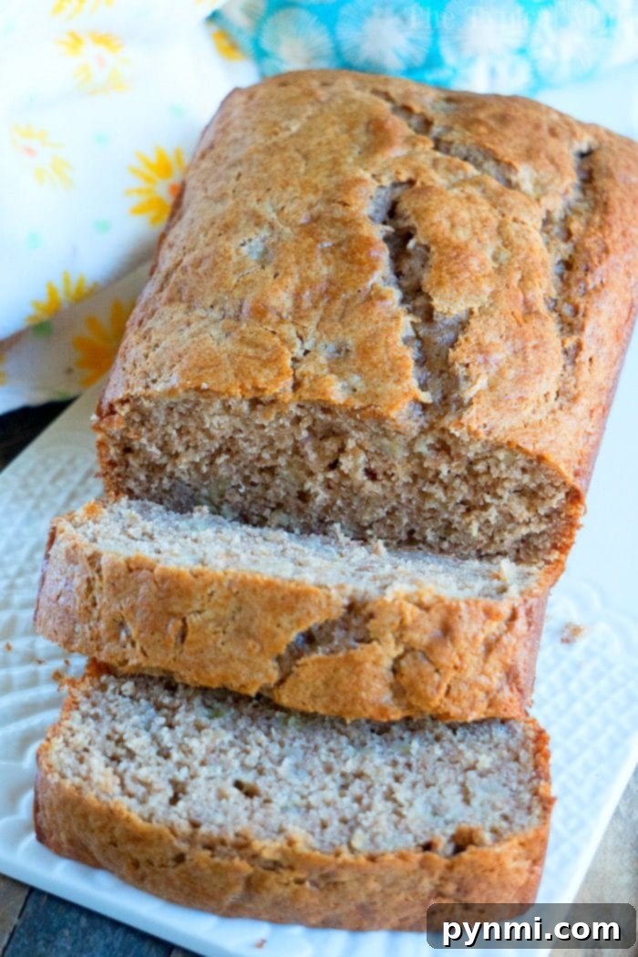 Two loaves of 4-ingredient banana bread with cake mix, one whole and one partially sliced, on a wooden surface.