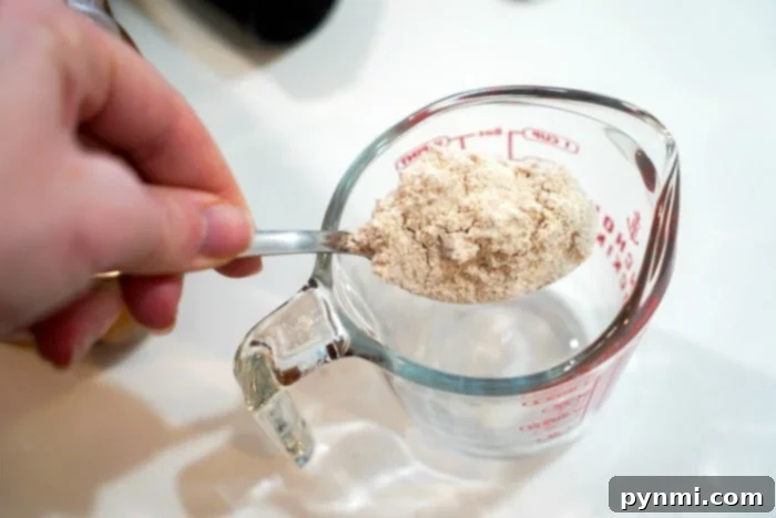 Effortless Whole Wheat Bread in a Bag 2 A measuring cup filled with whole wheat flour, ready to be added to the bread mixture.