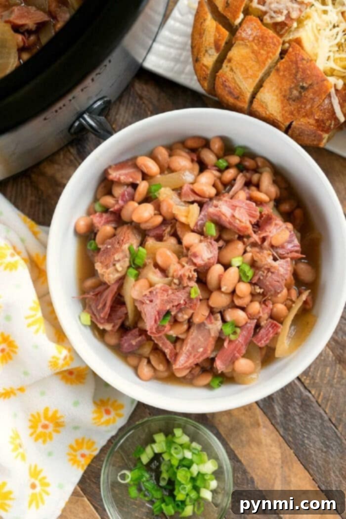 A close-up of slow cooker ham and beans, showcasing the rich broth, perfectly cooked beans, and chunks of ham, ready to be served.