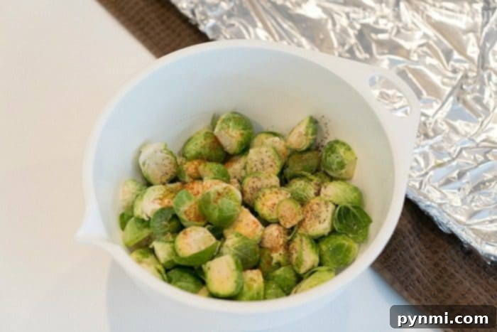This easy brussel sprouts recipe is a perfect side dish with a tangy sauce that just makes these vegetables addictive enough to start loving brussels! #brusselsprouts #baked #best #brussels #mustard #vegetables #sidedish A bowl of seasoned halved Brussels sprouts sits on the kitchen counter, ready to be baked. Wondering how long to bake Brussels sprouts at 450 degrees? They'll become perfectly crispy in about 20-25 minutes.