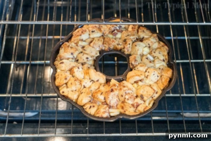 This apple monkey bread is packed full of fresh apples and really delicious! The best monkey bread I've made with refrigerated cinnamon rolls ever. #monkeybread #apple #breakfast #cinnamonroll #best #thetypicalmom Pillsbury cinnamon roll monkey bread with fresh apples, ready to be glazed.