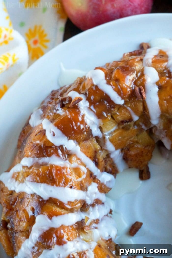 This apple monkey bread is packed full of fresh apples and really delicious! The best monkey bread I've made with refrigerated cinnamon rolls ever. #monkeybread #apple #breakfast #cinnamonroll #best #thetypicalmom Close-up of apple monkey bread, drizzled with vanilla icing after being flipped.