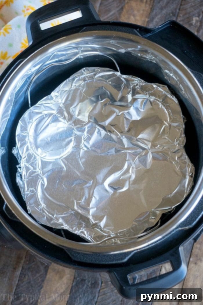 Pressure cooker egg bites are the perfect protein packed breakfast for busy mornings. A great Keto Instant Pot recipe with just a few ingredients. #instantpot #eggbites #starbucks #keto #instantpotrecipes #pressurecooker #crockpotexpress #thetypicalmom Instant Pot Egg Bites mold covered with aluminum foil, inside the pressure cooker