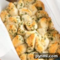 Golden, bite-sized Refrigerated Biscuit Pull Apart Bread pieces topped with parsley in a parchment-lined baking dish.