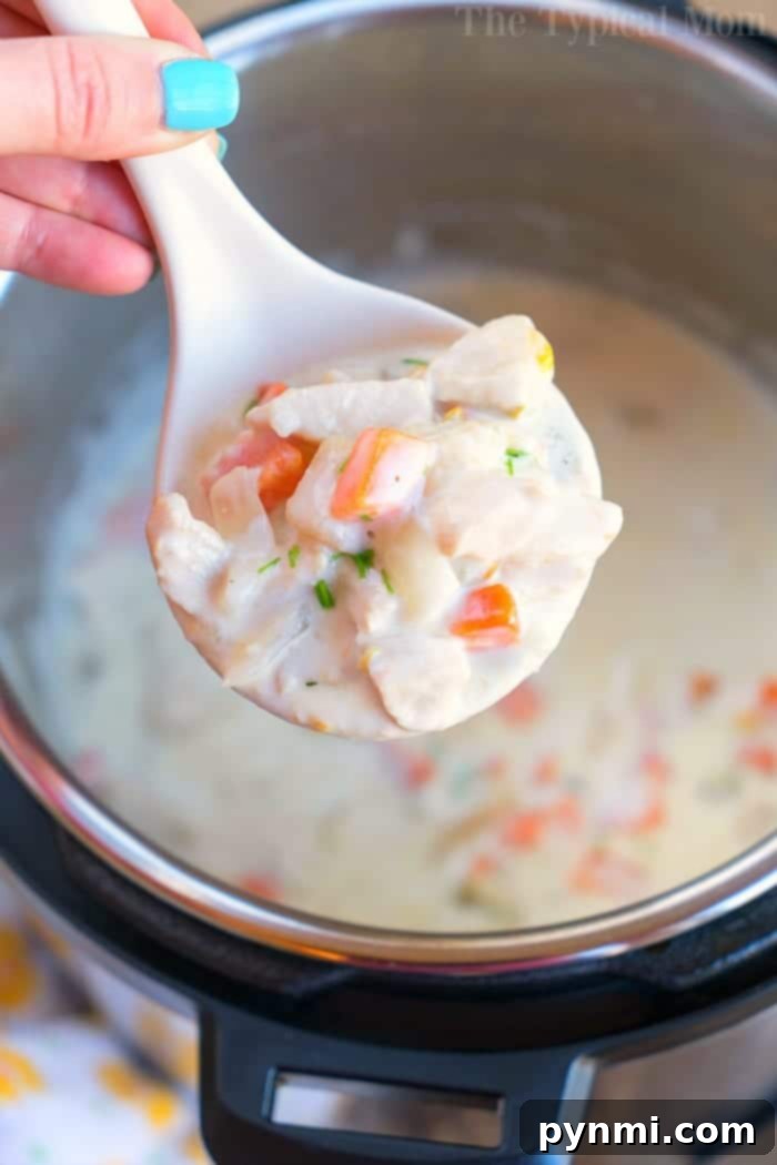 A large pot of creamy pressure cooker chicken pot pie soup, garnished with fresh herbs, ready for serving.