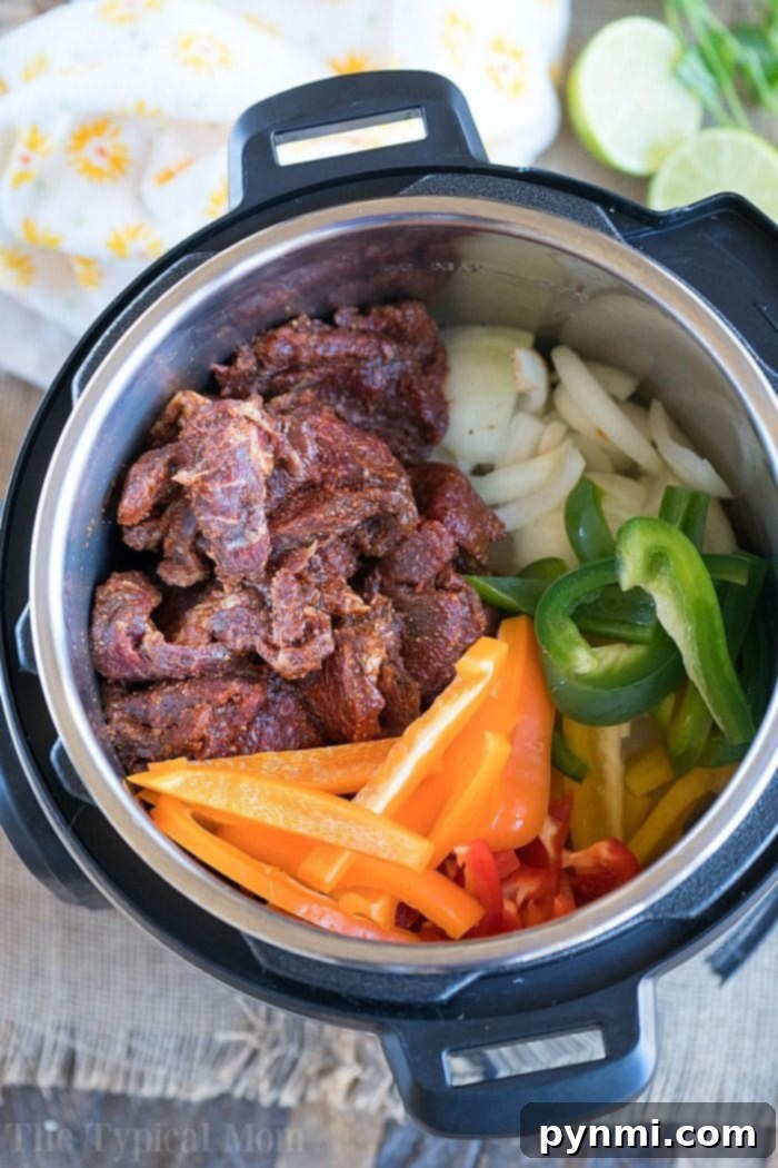 Serving of Instant Pot Fajitas in a bowl, garnished with cilantro and lime
