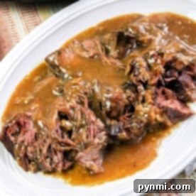 Tender pot roast, cooked to perfection in a pressure cooker, is smothered in gravy on a white plate, served on a striped tablecloth.