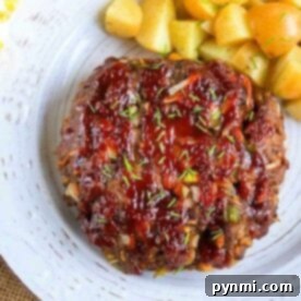 Pressure cooker meatloaf with herbs is elegantly glazed and served on a white plate, paired with perfectly roasted potato cubes.