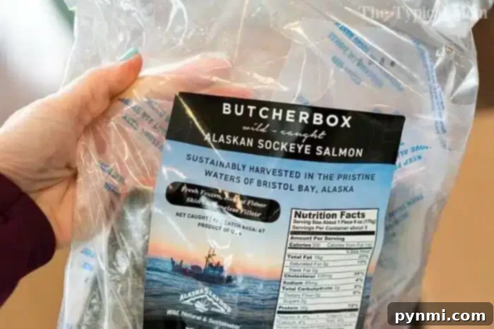 A hand holding a package of ButcherBox wild-caught Alaskan sockeye salmon, excellent for quick pressure cooker fish meals.