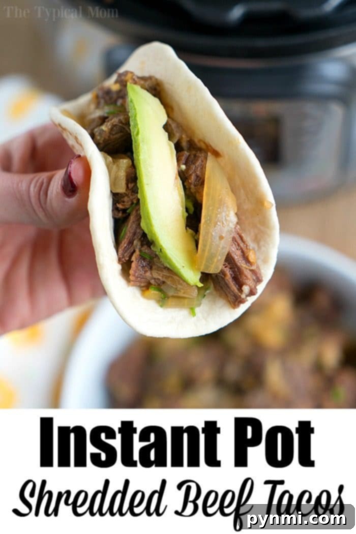French onion pressure cooker roast is tender with tons of flavor. Perfect Instant Pot shredded beef tacos for dinner even your kids will rave about. #instantpotrecipes #instantpot #roast #frenchonion #tacos #shreddedbeef #ninjafoodirecipes #crockpotexpressrecipes #pressurecookerrecipes A hand holds a delicious shredded beef taco, filled with tender, pressure-cooked blade roast, creamy avocado, and fresh onions in a soft tortilla.