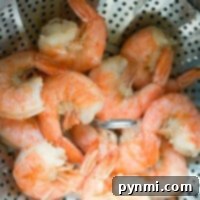 Fast Instant Pot Shrimp Recipe 8 Steamed shrimp cooked to perfection in an Instant Pot, nestled in a metal basket with a perforated design.