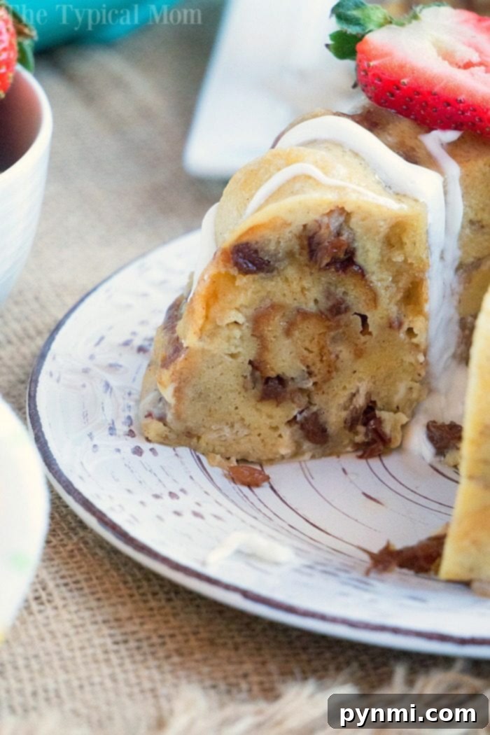 A slice of decadent bread pudding with white icing sits gracefully on a decorative plate, crowned with sweet strawberry slices—a delightful treat that rivals even the richest instant pot bread pudding.