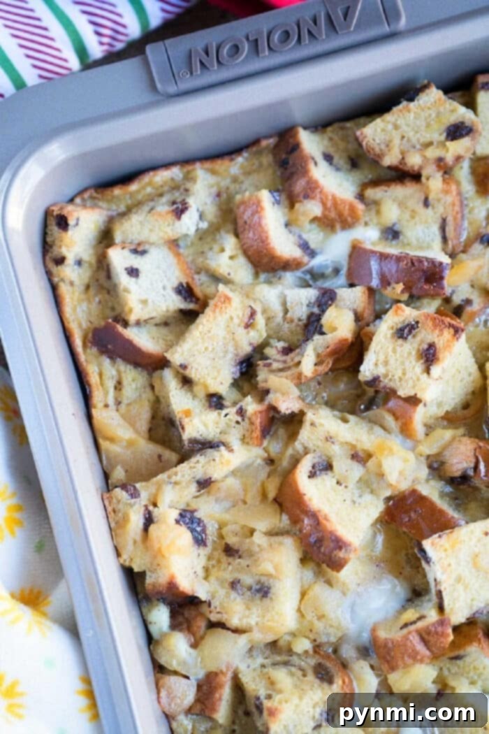 A serving of raisin bread pudding on a plate, garnished with a light drizzle of icing, ready to be enjoyed.