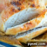 Close-up of a pressure cooker beer can chicken with golden, crispy skin and slices revealing tender, juicy white meat.