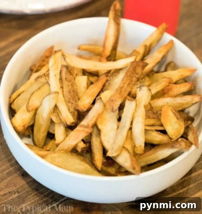 Perfectly Crispy Ninja Foodi Fries 7 A beautifully presented bowl brimming with golden-brown homemade French fries, perfectly crisped using the Ninja Foodi, resting on an inviting wooden table, ready for enjoyment.
