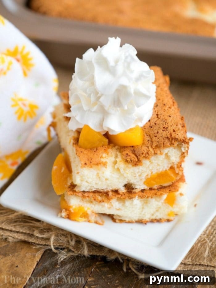 Easy 2 Ingredient Peach Angel Food Cake with Canned Peaches A perfectly sliced piece of Peach Angel Food Cake, topped with a dollop of fluffy whipped cream, rests on a pristine white square plate. The cake's light, airy texture is visible, studded with tender peach chunks. In the background, a decorative cloth and the baking dish hint at the cake's homemade charm, inviting you to indulge in this simple, fat-free dessert.