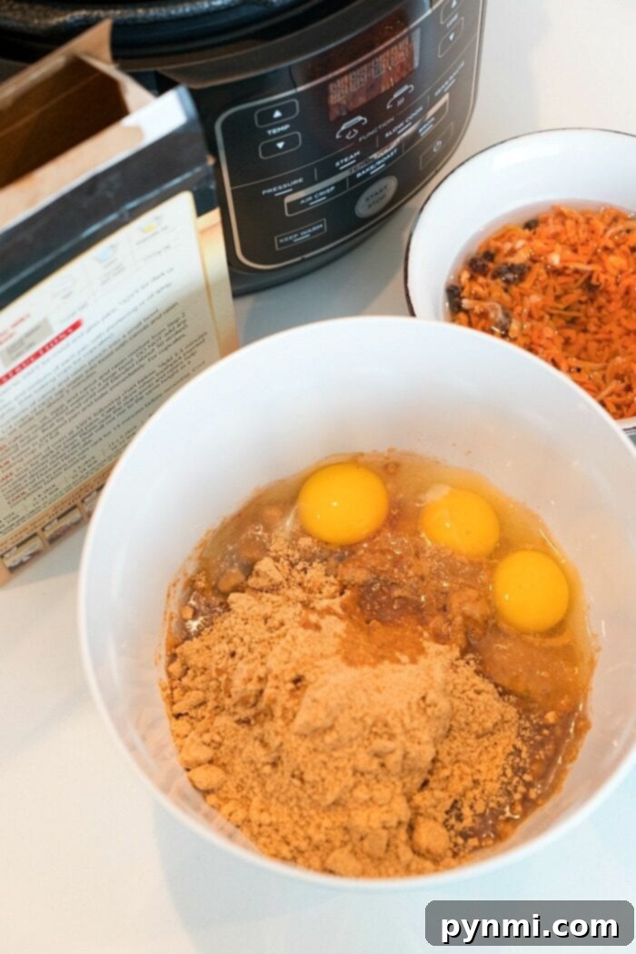 A bowl with eggs and brown mix sits alongside a Ninja Foodi cake, with an Instant Pot and various ingredients scattered in the background on a kitchen counter.