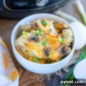 Bowl of cheesy breakfast casserole with green onions, made in the Ninja Foodi, next to eggs and a kitchen appliance in the background.
