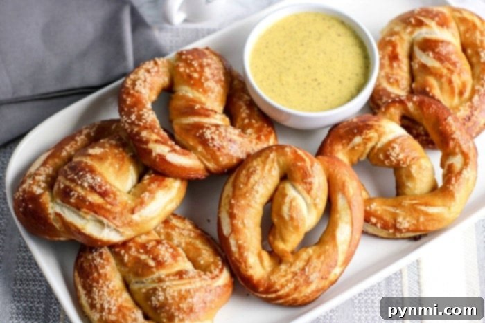 Two large, golden-brown soft pretzels, freshly baked and lightly salted, on a wire rack.