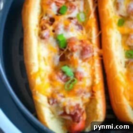 Crispy Air Fryer Franks 4 An air fryer hot dog topped with chili, melted cheese, and chopped green onions in a toasted bun.