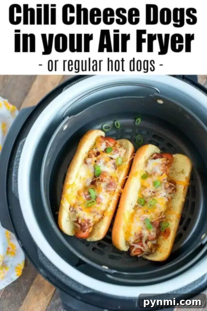 Air Fryer hot dogs or chili dogs are the perfect quick dinner idea our whole family loves! Load your buns up with toppings & they come out nice & crispy. #airfryer #hotdogs #chilidogs #ninjafoodi #ninjafoodirecipes Two chili cheese hot dogs adorned with melted cheese and vibrant sliced green onions, perfectly presented in an air fryer basket.