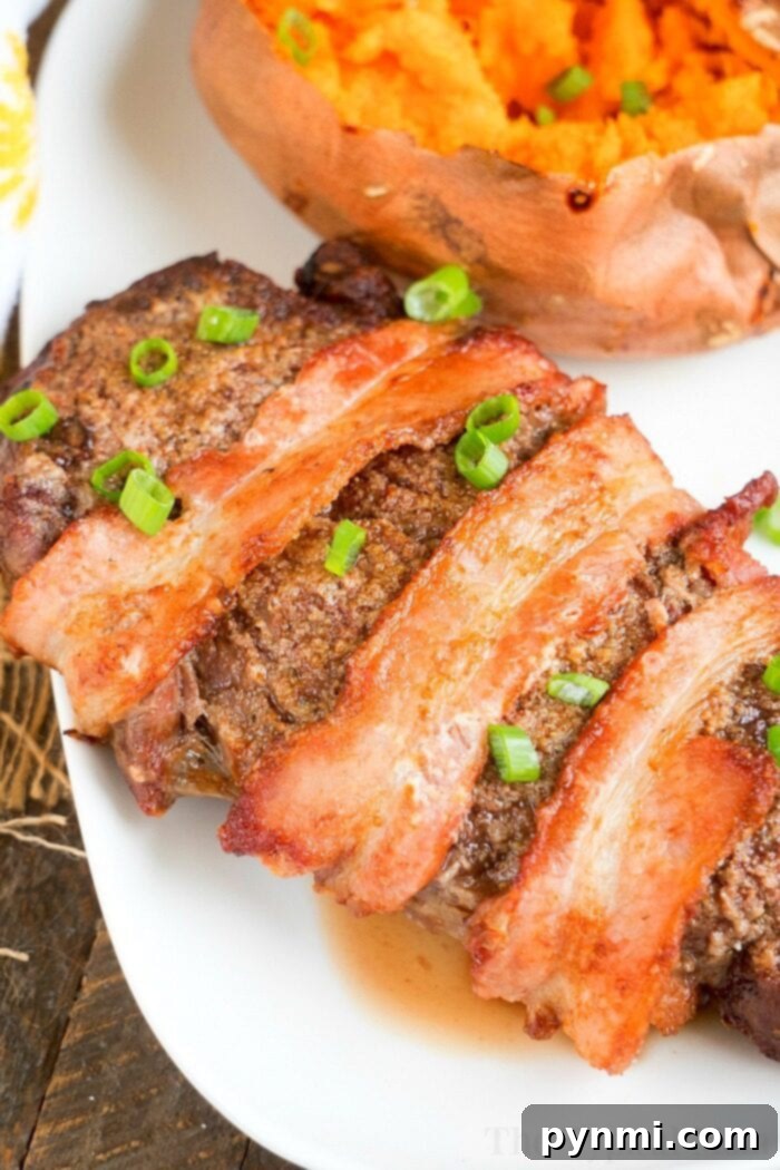 Bacon-wrapped steak garnished with green onions sits elegantly beside a baked sweet potato on a white plate, reminiscent of an air fryer steak in its perfection.