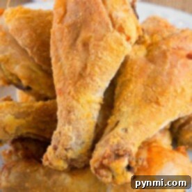 A plate of crispy, golden-brown air fryer fried chicken drumsticks piled together.