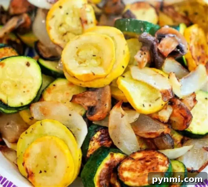 Best air fryer vegetables you will ever make are here! No breading, just seasonings and mixed vegetables cooked to perfection. A healthy side dish fave. #ninjafoodi #airfryer #airfryerrecipes #vegetables #mixedvegetables #ninjafoodirecipes #ninjafoodigrill #mushrooms #zucchini #yellowsquash A vibrant dish of air fryer vegetables, including sautéed yellow squash, zucchini, mushrooms, and onions. The thinly sliced and seasoned veggies exhibit a beautiful golden-brown crispness from air frying, presented attractively on a plate.
