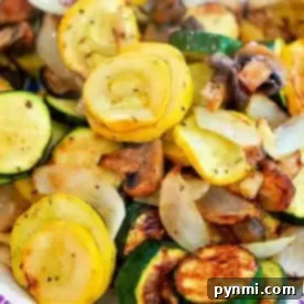 A dish featuring air fryer vegetables, including sautéed yellow squash, zucchini, mushrooms, and onions. The sliced veggies are seasoned to perfection with a delightful browning from cooking. This colorful mixture is beautifully presented on a plate.