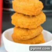 A stack of golden, crispy air fryer chicken nuggets, fresh from the freezer and perfectly cooked.