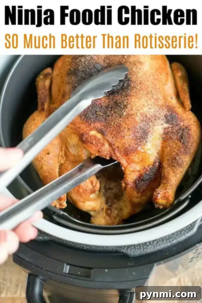 A whole roasted chicken is being lifted out of a Ninja Foodi cooker using metal tongs. The text above reads "Ninja Foodi Air Fryer Chicken: SO Much Better Than Rotisserie!