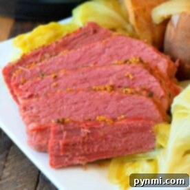 Slices of tender corned beef with cabbage and potatoes grace a white plate, revealing the magic of a Ninja Foodi in transforming this classic dish into a perfectly cooked masterpiece.