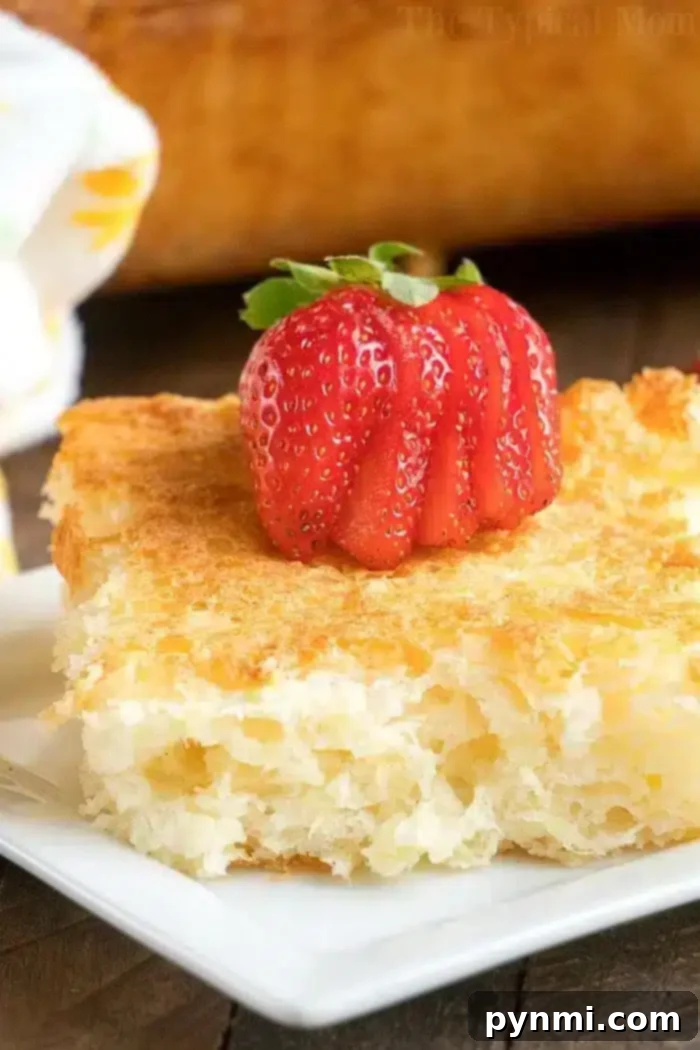 A close-up of a piece of golden-brown bread pudding on a white plate, topped with a strawberry sliced fan-like. 