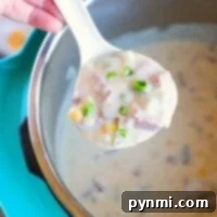 A spoonful of creamy corned beef soup with ham and green onions hovers above the pot, promising a savory delight.