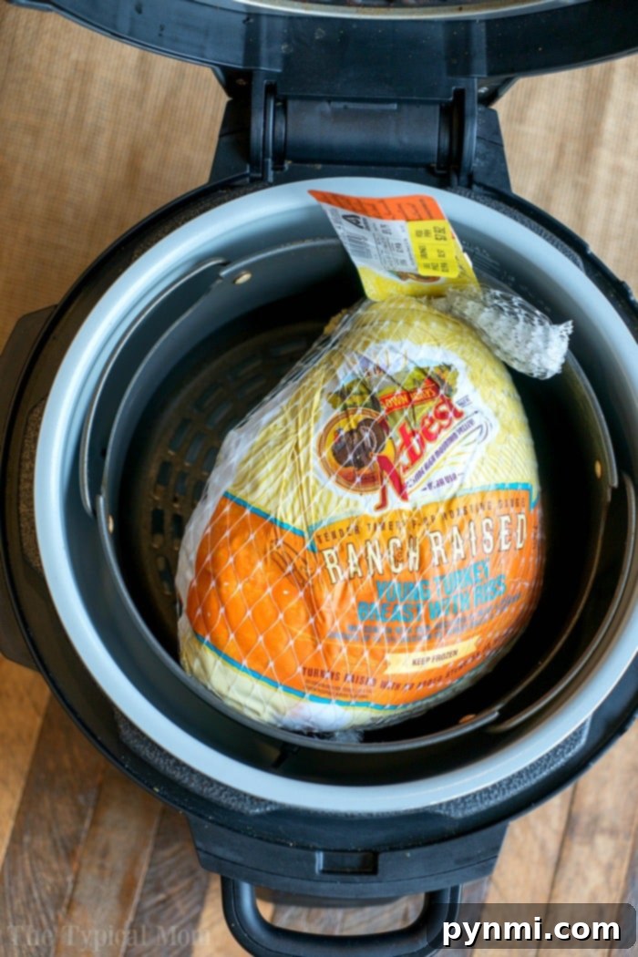 Ninja foodi turkey breast that's tender inside and crispy on the outside! Learn how to cook a bone in turkey breast in your Ninja Foodi or Instant Pot. Turkey breast, still in its netting, perfectly nestled inside an open Ninja Foodi on a rustic wooden surface, ready for cooking.