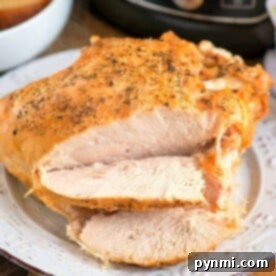 Sliced roasted turkey breast, prepared to perfection in a pressure cooker, rests on a white plate adorned with fresh herbs, with the Ninja Foodi subtly visible in the background.