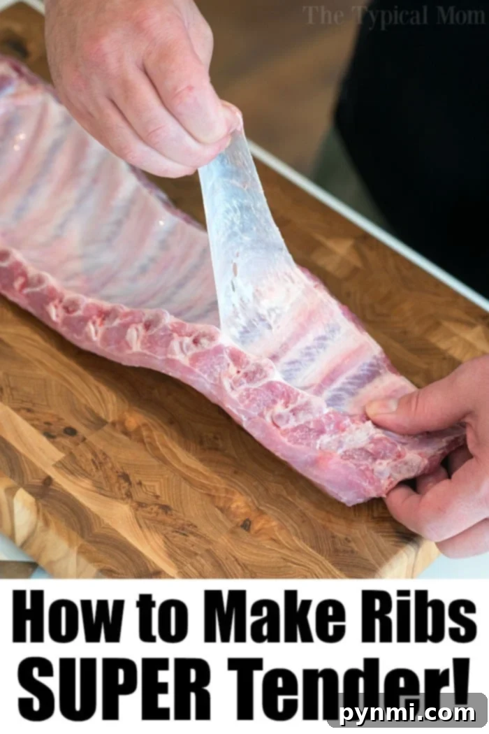 Hand gripping and pulling the rib membrane cleanly off a rack of ribs