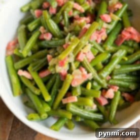 A bowl of sautéed green beans, perfected in the Ninja Foodi, mixed with diced bacon and onions.