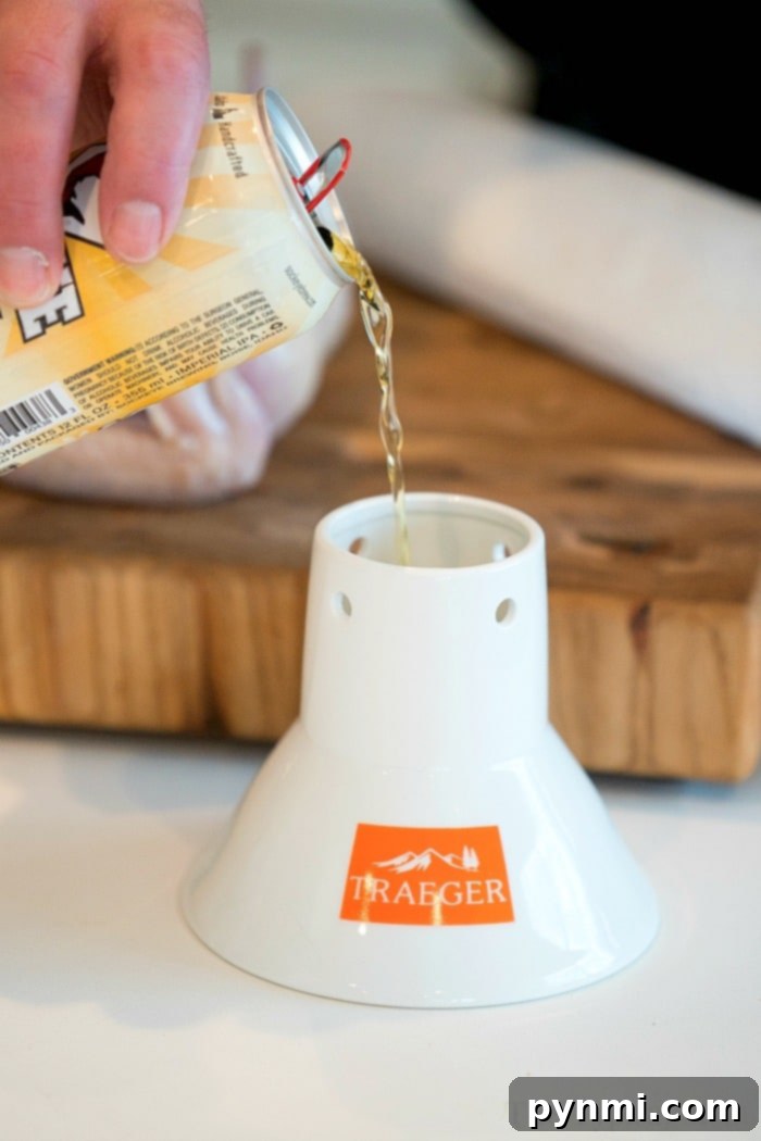 A person skillfully pours beer into a white Traeger chicken throne on a wooden countertop, preparing the perfect base for a delicious smoked beer can chicken.