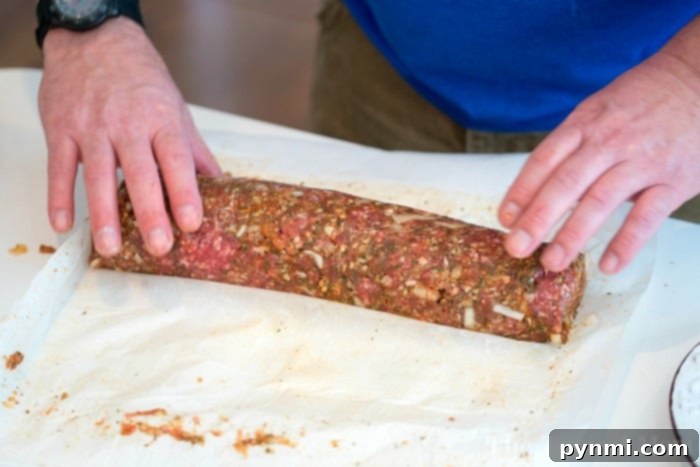 A delicious smoked meatloaf roll, stuffed with cheese and bacon, resting on a grill plate after being perfectly cooked. The golden-brown exterior and visible melted cheese promise an amazing comfort food experience. This shows how to make the best smoked meatloaf.